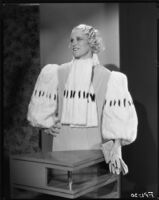 Peggy Hamilton modeling an evening gown with wide fur sleeves, 1933