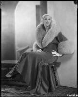 Peggy Hamilton modeling an Adrian full-length coat trimmed with fur, circa 1929-1933