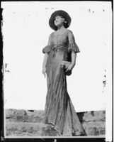 Peggy Hamilton modeling a lace evening gown and wide-brim hat, circa 1929-1933