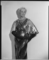 Peggy Hamilton modeling a Travis Banton gown of black net with gold palettes and sequins, 1931