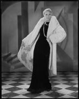 Peggy Hamilton modeling a white ermine coat over a black velvet evening gown, 1930