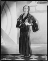 Peggy Hamilton modeling a black velvet dinner gown and metallic brocade jacket, 1930
