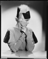 Peggy Hamilton modeling a hat and a dress with dolman sleeves and fur epaulettes, 1933