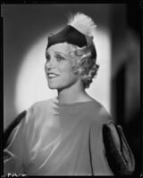 Peggy Hamilton modeling a dress with dolman sleeves and fur epaulettes and a hat, 1933