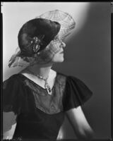 Peggy Hamilton modeling a hat with a wide net brim and catalin bakelite trim, 1933