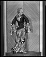 Peggy Hamilton modeling an evening gown with bell sleeves and a peplum, 1931