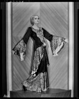 Peggy Hamilton modeling an evening gown with bell sleeves and a peplum, 1931