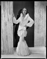 Actress Loretta Young modeling a white ermine spring jacket over a pale pink ruffled net gown, 1931