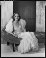 Actress Loretta Young modeling a white fox stole over a pale pink spring evening gown of ruffled net, 1931