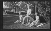 Three float riders in gowns posing in front of a house before the start of the Tournament of Roses Parade, Pasadena, 1930