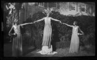 Three float riders in gowns posing in front of a house before the start of the Tournament of Roses Parade, Pasadena, 1930