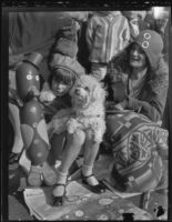 Little girl and her dog seated curbside to watch the Rose Parade, Pasadena, 1930