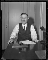 Politician Justus Wardell seated at a desk, 1933