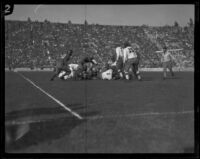 USC Trojan player lies in the middle of a huddle with possesion of the football during a game against Stanford, Los Angeles, 1925