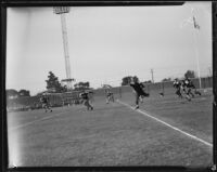 Loyola football player reaches for a pass during a game against San Francisco University, Los Angeles, 1932