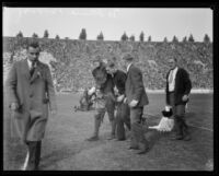 Injured football player is escorted off the field during the USC and Notre Dame game, Los Angeles, 1928