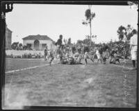 Two Occidental players fall on the ground and try to gain possession of the football during a game against Whittier College, Whittier, 1925