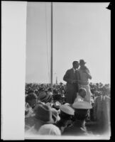 Art Goebel and Victor Clark stand on a podium and address a crowd at Mines Field, Los Angeles, 1928