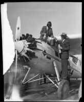 Art Goebel stands up from the cockpit of the "Yankee Doodle" monoplane to receive food and drink from Victor Clark, Los Angeles, 1928