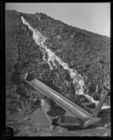 Water flows down a hillside and towards blast-damaged pipes of the Los Angeles Aqueduct in No-Name Canyon, Inyo County vicinity, [circa 1927]