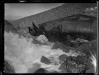 Water rushes over rocks near a dynamited section of pipe along the Los Angeles Aqueduct in No-Name Canyon, Inyo County vicinity, [about 1927]