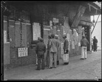 Men read notices posted on a building in Chinatown, Los Angeles, 1920-1939