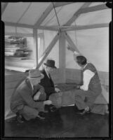 Men use a blueprint to examine one of the tents that is used for a classroom, Los Angeles, 1935