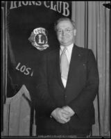 Dr. Thomas F. Madden standing in front of Lions International banner, Los Angeles (?), between 1934-1935 (?)