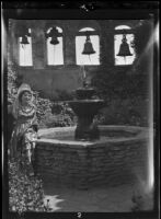 Woman seated beside a fountain at Mission San Juan Capistrano, 1930s