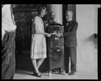 Francis Griffith, A. B. Foster, and postmaster P. P. O'Brien try out stamp vending machine, Los Angeles, 1929