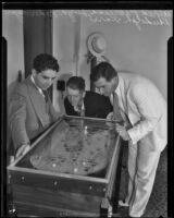 Judge Alfred Paonessa and Randolph Kerr watch Lloyd Federmeyer show his skills on a marble game, Los Angeles, circa 1934