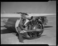 Unidentified man inspects the damaged propeller on Wiley Post's airplane, Winnie Mae, Muroc Dry Lake, circa 1935
