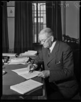 Ned Powell, city treasurer, writing at his desk, Los Angeles, 1934
