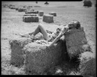 Mrs. Joe Raymond reclining on baled hay, San Fernando Valley, 1946