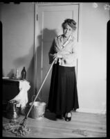 Mrs. Flournoy, in cardigan with holes, mopping floor, [1950s]