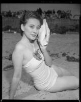 Betty Herrick [?] on beach with seashell, 1953-1964