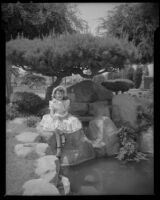 Helena Burnett in dress and bonnet sitting next to a pond, 1947-1950