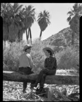 Paul P. Wilhelm and Marcella seated on a log at 1000 Palms Ranch, Thousand Palms vicinity, 1939