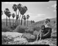 Paul P. Wilhelm dressed in Arabic style clothing with a child at 1000 Palms Ranch, Thousand Palms vicinity, 1939