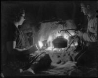 Paul P. Wilhelm and Marcella cooking in a fireplace at night at 1000 Palms Ranch, Thousand palms vicinity, 1939