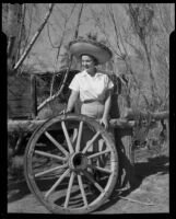 Dorie Doney standing next to a wagon wheel at 1000 Palms Ranch, Thousand Palms vicinity, 1941