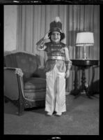 Barbara Lee Tramutto wearing a soldier costume and saluting in a living room, 1940-1945
