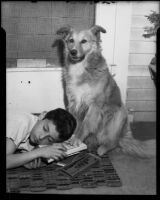 Boy resting on doormat with dog, [1940s or 1950s?]