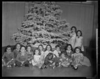 Children, perhaps dance students of Julia Stewart, seated beneath a Christmas tree, probably Santa Monica, 1957