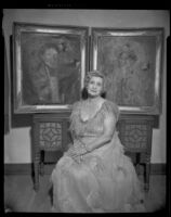 Pegg Connell Phipps (?) seated in front of portraits of the Count and Countess De Grasse, Santa Monica, 1956