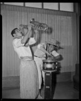 Two young men in tropical costumes playing musical instruments, 1950-1960