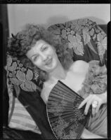 Portrait of a woman with a fan reclining on a pillow, Santa Monica, 1940-1960