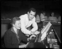 Pianist or opera singer at a piano with a man looking on in the orchestra pit of a theater, 1958