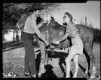 Cowboy Johnny Boyle helping Mona Ohrtland to with a horse, Palm Springs, 1940