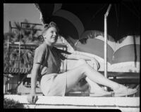 Mona Ohrtland seated beneath a sun umbrella, Palm Springs, 1940